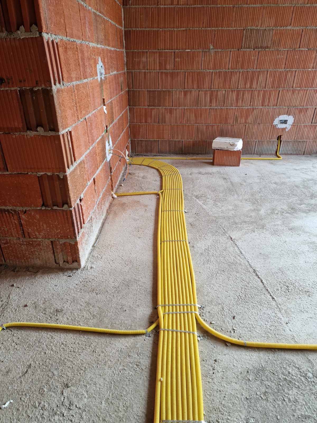 Degëzim i tubave elektrikë përgjatë murit të tullave